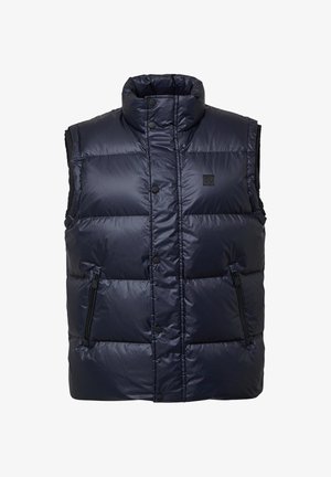 Tumedast sinine vatitatud vest kõrge kraega, esiküljel nööbid, ja kaks lukuga küljetaskut; hõlmab rinnal logo.