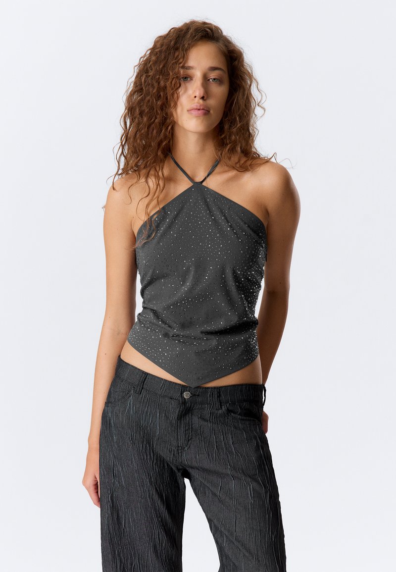 Sivý halter top s kamienkovými akcentmi, priliehajúci strih a trojuholníkový lem. Skombinovaný s texturovanými tmavými nohavicami. Hladká textúra látky.