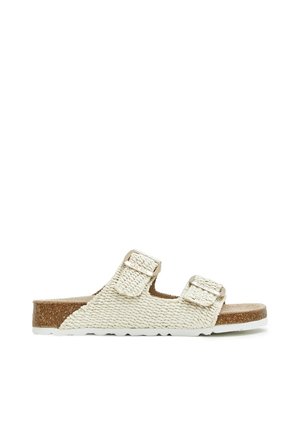 Sandalia deslizante beige tejida con dos correas ajustables, plantilla de corcho y suela de goma blanca, mostrada de perfil.