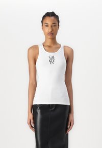 White tank top with a round neckline, featuring a black graphic logo centered on the front. Smooth cotton material, fitted design.