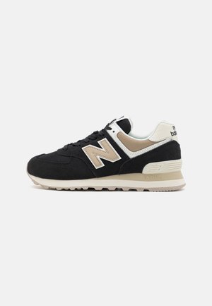 Zwarte en beige New Balance sneaker van suede en mesh materialen, met een opvallend "N" logo en een rubberen buitenzool.