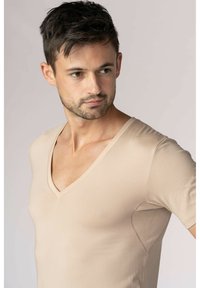 Beige v-ringad t-shirt i stretchtyg. Har korta ärmar, figurnära passform, slät textur och subtila sömdetaljer på sidorna.