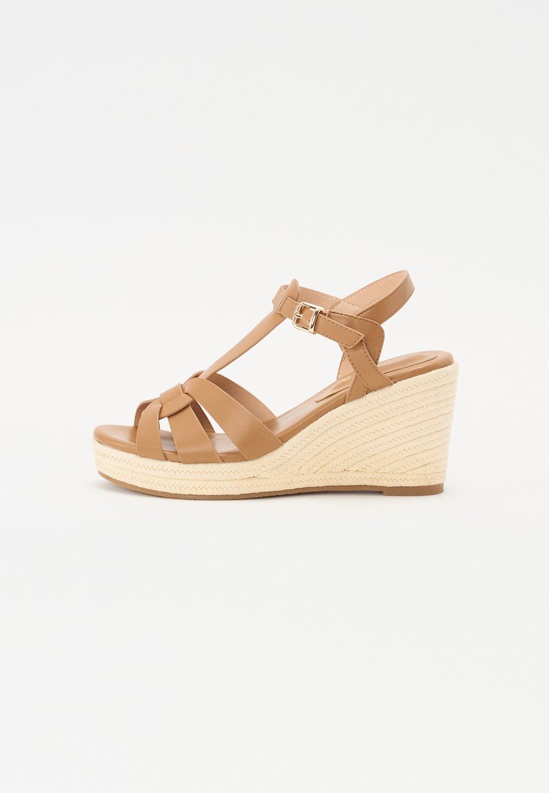 Sandales compensées en tan avec un design à lanières croisées, boucle réglable à la cheville et une semelle compensée en espadrille tissée texturée.