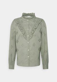 Lichtgroene katoenen shirt met kantafwerking, voorzien van gaatjespatronen, lange mouwen en knoopsluiting. Versierd met decoratieve uitsparingen.