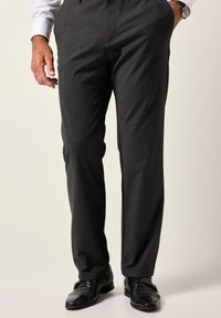 Pantalones de vestir grises con tela texturizada, diseño de pierna recta y pliegues planchados. Combinados con zapatos de cuero negros.