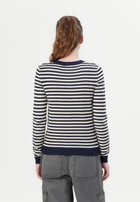 Puloverstripat în tonuri de navy și crem, cu gât rotund ribultat și manșete strâmte. Fabrică de tricot moale, cu mâneci lungi și o siluetă lejeră.