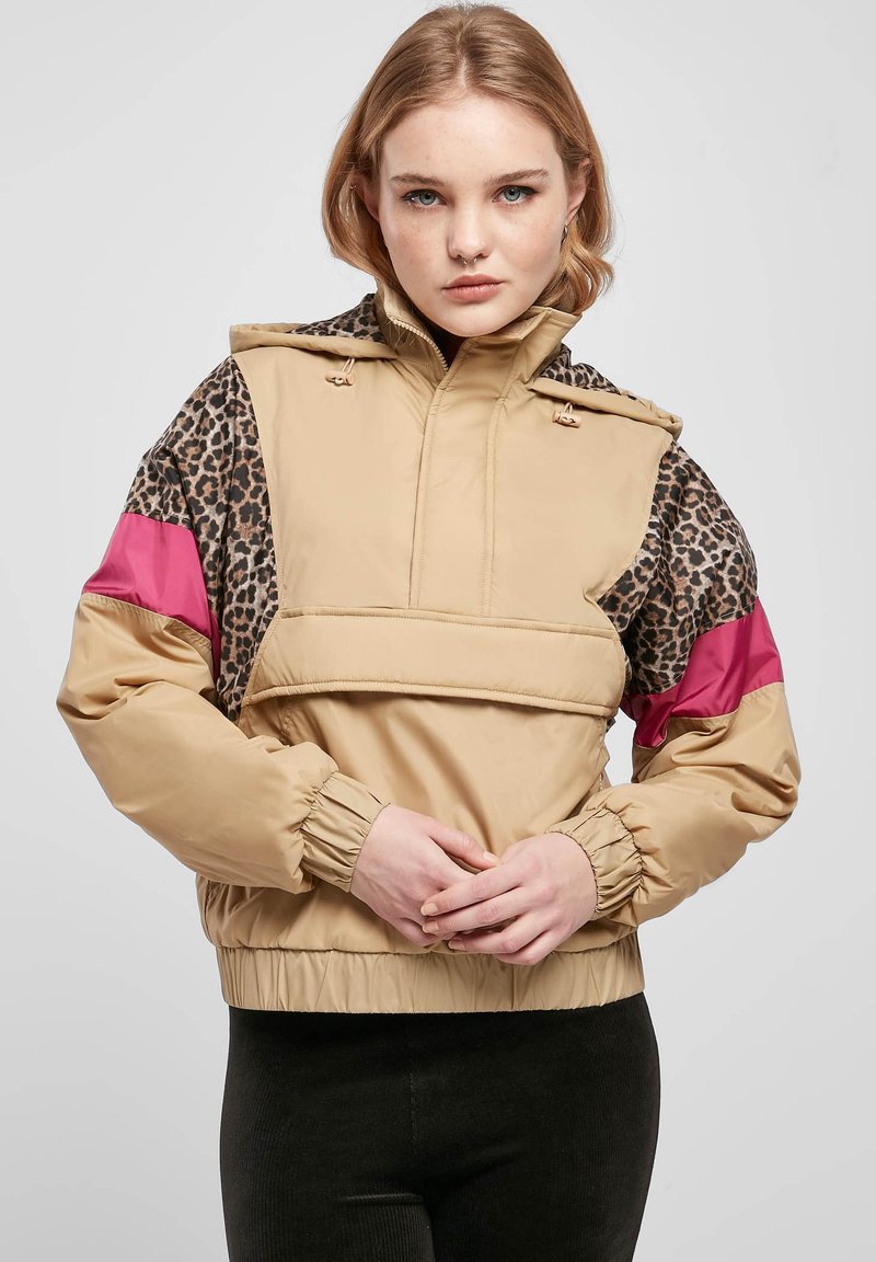 Beige hettegenser med leopardmønstrede ermer og fuchsia-detaljer, med en frontlomme og elastiske mansjetter. Glatt, teksturert stoff.