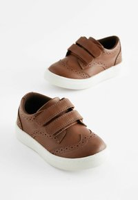 Baskets en cuir marron avec deux sangles Velcro, semelles en caoutchouc blanches et perforations décoratives sur les côtés. Conception à bout arrondi.