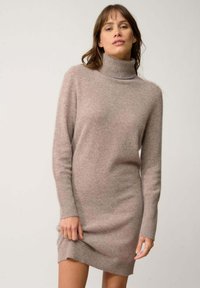 Vestito maglione a collo alto in morbido tessuto color marrone chiaro. Maniche lunghe, polsini e orlo a costine, silhouette aderente e texture liscia.