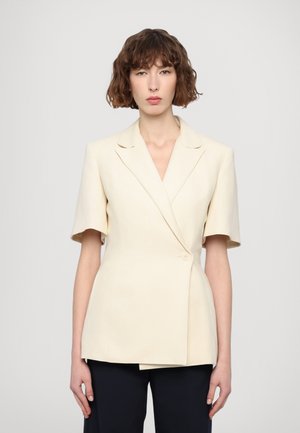 Hochgeschneiderte, cremefarbene Blazer mit kurzen Ärmeln, V-Ausschnitt und einem einzelnen Knopfverschluss; strukturierten Stoff mit dezentem Glanz.