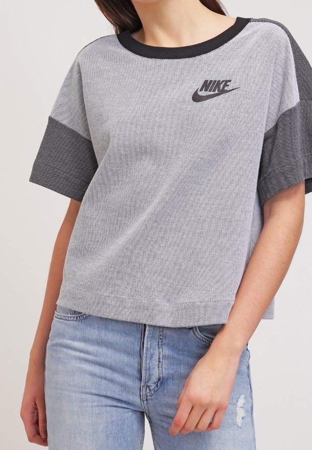 Grijs Nike T-shirt met korte mouwen en zwarte accenten, met een gestructureerd ontwerp en logo op de borst. Het materiaal is licht en casual.