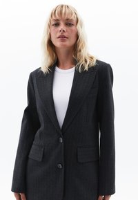 Mørkegrå stribede blazer med to frontlommer, enkeltknaplukning og skræddersyet pasform. Glat stof med en struktureret design.