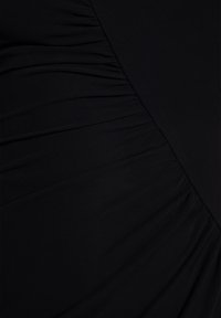 Czarna tkanina na suknię z marszczonymi teksturami, z ukośnymi panelami. Materiał jest gładki, co nadaje elegancki wygląd.