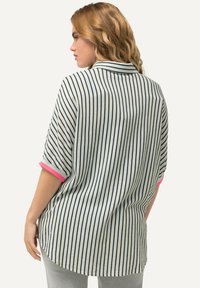 Top leggero a righe con strisce verticali blu e bianche, maniche arrotolate rosa e orlo curvo. Morbido, con una vestibilità rilassata.