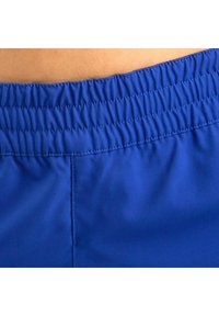 Pantaloni da bagno blu con cintura elastica, caratterizzati da cuciture arricciate lungo il bordo superiore e una texture liscia e leggera.