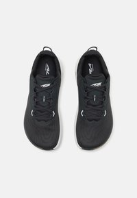 Baskets de sport noires avec une tige en maille texturée, bout rond, col rembourré et semelle blanche contrastante. Comprend des lacets et des accents réfléchissants.