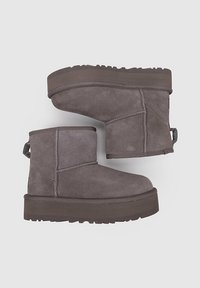 Botas de ante gris hasta el tobillo con puntera redonda y suela gruesa. Costuras destacadas que acentúan el diseño y una tira trasera para facilitar el calzado.