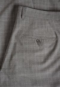 Grå tygbyxor med ett fint rutmönster, med en bakficka med knapp och en slät textur.