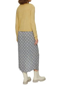 Light yellow sweater, patterned long skirt in blue and white flowers, cream ankle boots with textured soles, side view, relaxed fit.