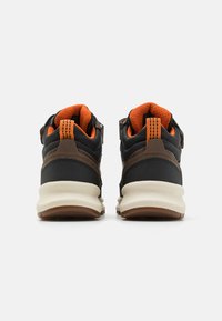 Chaussures de sport noires et brunes avec des accents orange, tige texturée, talon robuste et semelle rembourrée. Comprend une languette à l'arrière pour un enfilage facile.