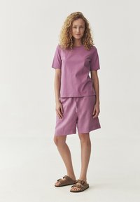 Light purple cotton t-shirt and matching shorts, with a relaxed fit and short sleeves. Paired with brown sandals, standing on a neutral background.