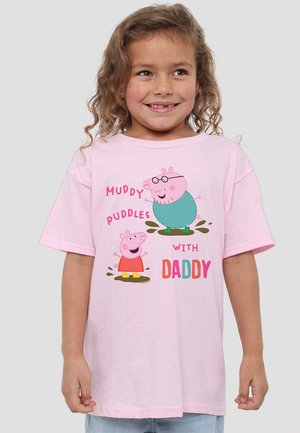 Helles rosa T-Shirt mit Cartoonfiguren einer Schweinefamilie, die in schlammigen Pfützen plantschen, mit dem fett gedruckten Text "SCHLAMMIGE Pfützen MIT PAPA."