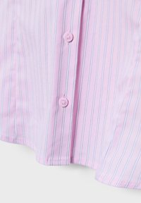 Nahaufnahme eines pinkfarbenen Stoffs mit vertikalen, dünnen schwarzen und weißen Streifen, versehen mit zwei pinkfarbenen Knöpfen, die entlang der Knopfleiste angenäht sind.