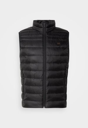 Svart isolert vest med høy krage, glidelås og horisontal quiltet mønster. Har sidelommer og en liten logostropp.