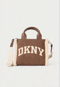 Ruda DKNY New York rankinė su kreminės spalvos vilnoniu apvadu, viršutinėmis rankenomis ir reguliuojamu petnešėliu ant šviesaus vientiso fono.