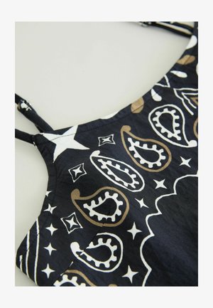 Black fabric top featuring a paisley and star pattern in white and gold accents, with thin straps and a rounded neckline.