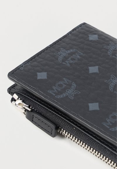 Black leather wallet with embossed MCM logo pattern, silver zipper hardware, and textured finish. Compact design with a sleek silhouette.