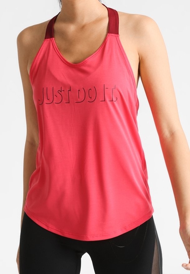 Femme portant un débardeur de sport rouge avec le texte « JUST DO IT » et un legging noir, visible des épaules aux hanches sur un fond blanc.