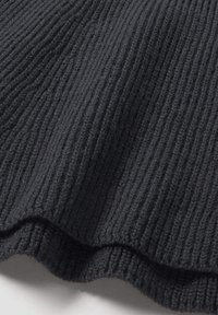 Zwart rib gebreide stof met een gestructureerde afwerking en een golvende rand. Het materiaal lijkt zacht en rekbaar, geschikt voor diverse kledingstukken.