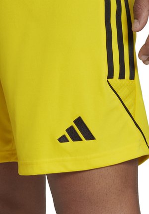 Geel sportshort met zwarte zijstrepen en een zwart Adidas-logo. Heeft een gladde stoftextuur en een ingebouwde mesh-zak.