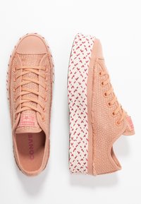 Brzoskwiniowe sneakersy z siateczki z okrągłym noskiem, tonowanymi sznurowadłami oraz teksturowaną białą gumową podeszwą z czerwonym geometrycznym wzorem.