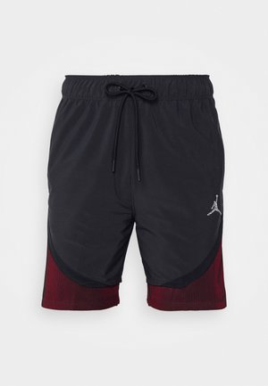 Shorts de sport noirs avec taille à cordon de serrage et design bicolore ; accents texturés rouges sur les côtés ; doté d'un logo argenté à l'avant.