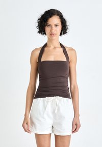 Brown, fitted halter top with a square neckline and gathered texture, paired with white drawstring shorts. Lightweight fabric, casual design.