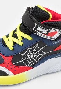 Sneakers per bambini con un upper in rete nera, sovrapposizioni in sintetico blu, accenti rossi, lacci giallo neon e una grafica a ragnatela.
