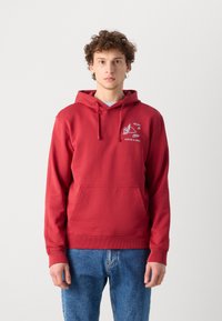 Red hoodie with a front pocket, featuring a white graphic design on the chest. Made of soft fabric, with ribbed cuffs and hem.