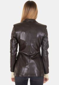 Blazer in pelle marrone dal taglio aderente, con colletto con revers e maniche slim. Texture liscia con dettagli di cuciture sul retro.