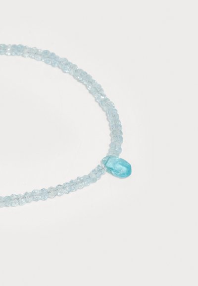 Delikatus kaklo papuošalas, pagamintas iš šviesiai mėlynų karoliukų, su didesniu ašaros formos akvamarino akmeniu kaip centriniu elementu.
