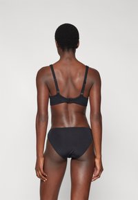 Zwart lingerieset met een eenvoudige beha met verstelbare bandjes en een bijpassende hoog-geprijsde onderkant, van gladde stof en met een minimalistisch ontwerp.