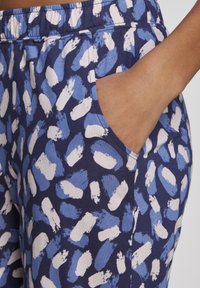 Blue patterned joggers made of soft fabric, featuring a navy base with abstract white and light blue brushstroke designs and pockets.