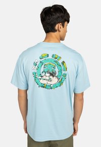 Light blue cotton t-shirt featuring a colorful graphic of a dog surrounded by bones and abstract shapes on the back. Short sleeves, relaxed fit.