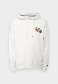 Lys grå hettegenser laget av mykt materiale, med en frontlomme, snor og en flerfarget brodert logo på brystet.