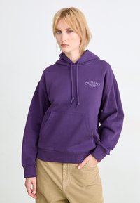 Violetti huppari, jossa on etutasku ja nyörityshuppu. Ominaisuuksiin kuuluu pieni harmaa "Carhartt WIP" -logo. Valmistettu pehmeästä kankaasta, rento malli.