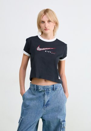 Black cropped t-shirt with white ribbed cuffs, featuring a red and checkered Nike logo and text. Worn with blue denim cargo pants.