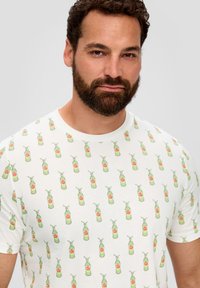 Witte t-shirt met korte mouwen, voorzien van een herhaald patroon van groene drankflessen met rode accenten, gemaakt van zachte katoen.