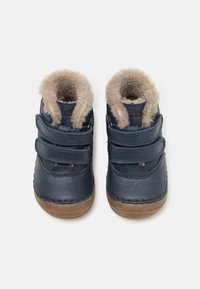 Pantofi pentru copii din piele bleumarin, cu două curele Velcro, căptușeală din blană moale și tălpi din cauciuc maro. Design cu vârf rotund și detalii cusute.