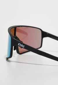 Lunettes de soleil noires avec des verres doubles ; verre gauche bleu, verre droit rose. Présente une monture noire élégante avec un logo sur la branche. Charnières ajustables.